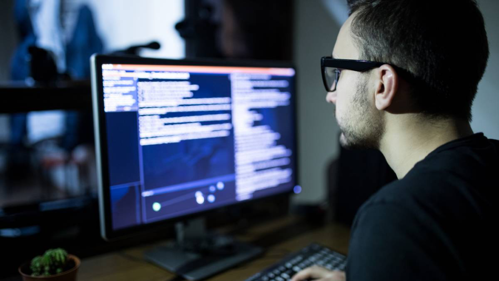 Man sitting in front of computer screen with code